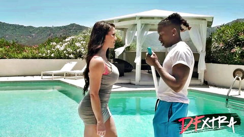 Busty brunette in tight gray dress flirts with muscular ebony stud by outdoor pool
