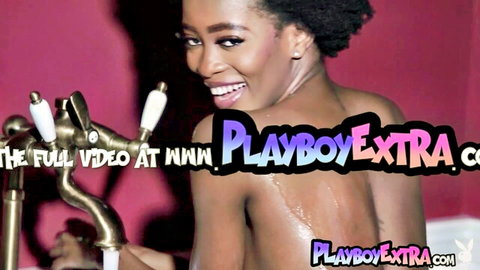 Nude ebony babe with petite body and natural tiny tits smiles over shoulder showing wet ass in bathtub