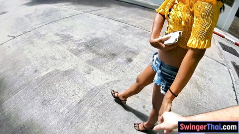 Petite Thai girl in tiny frayed denim shorts exposing ass walking hand-in-hand outdoors
