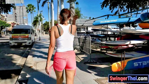 Thai amateur girl in white tank and pink shorts walking sunny street