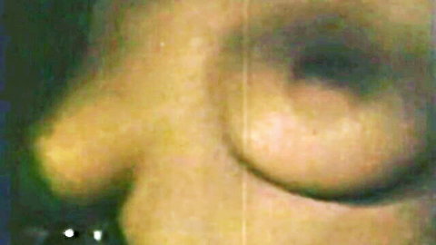 Vintage close-up of woman's erect dark nipple on large yellow-tinted breast