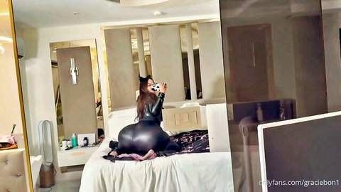 Curvy tanned Latina with huge ass in shiny latex pants poses doggy style on bed taking selfie