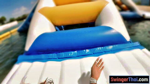 Petite Thai girl's hand on slippery white inflatable water slide in sunny outdoor park