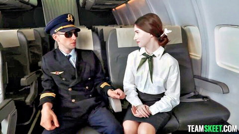 Young stewardess in uniform flirts with captain in airplane cabin