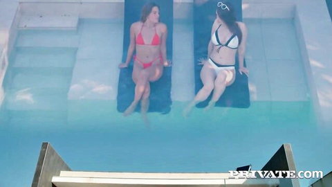 Two hot bikini babes lounging poolside showing off curves and tits in red and white bikinis