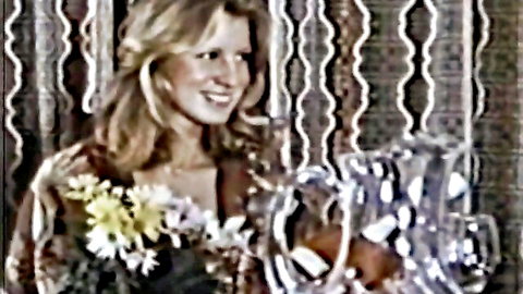 Smiling retro blonde woman in open dress holding flowers and pitcher