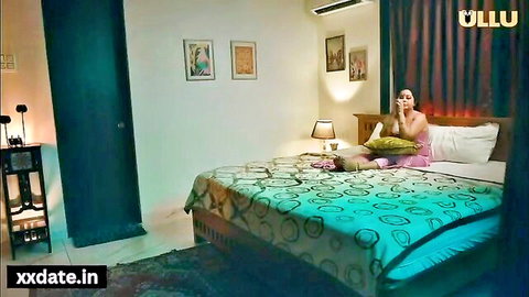 Indian MILF in pink top sitting on bed, texting seductively