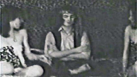 Retro vintage threesome: two long-haired women flanking shirtless man in antique Color Climax loop