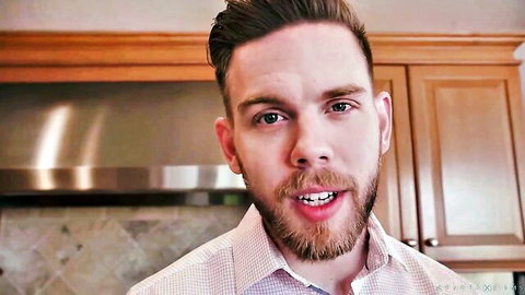 Bearded man smiling in checkered shirt with kitchen cabinets background