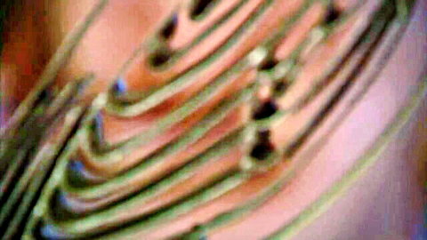 Blurry close-up of overlapping curved green-yellow tubes on reddish background