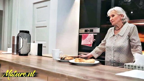 Sexy mature silver-haired woman in polka-dot pajamas posing in kitchen