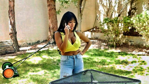 Sexy Latina in yellow halter top and ripped jeans on phone outdoors