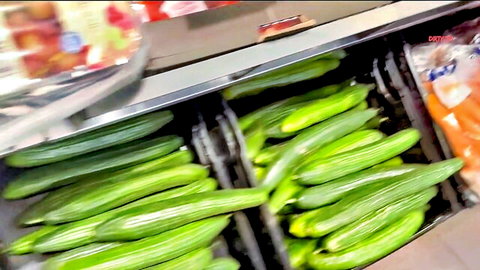 Stacks of thick long green cucumbers in supermarket bins resembling giant dildos