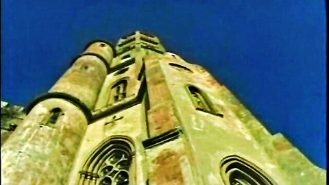Majestic medieval castle tower with gothic arches and turrets against vibrant blue sky