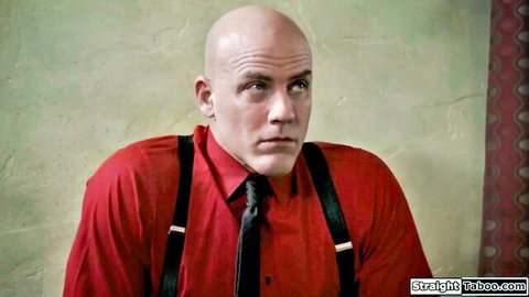 Bald muscular man in red shirt and suspenders stares intensely in Bridgette B adult scene