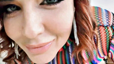 Seductive redhead with green eyes and plump lips smiling close-up in colorful top