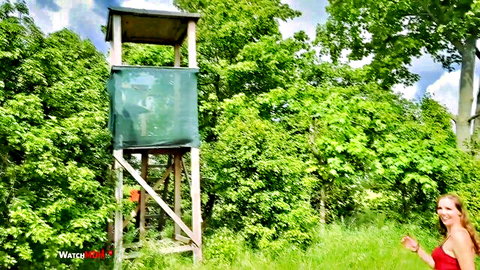 Miss_K poses in red dress by hunting tower in risky outdoor woods adventure