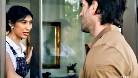 Brunette waitress in white shirt and apron talks intently to curly-haired man through glass door