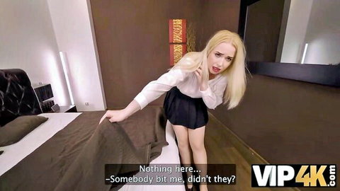 Blonde in short skirt and blouse bending over bed teasingly