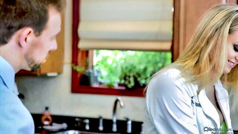Blonde in open lab coat flirts with man in romantic kitchen scene
