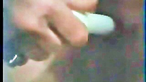 Hand gripping thick white dildo closeup in vintage retro porn video.