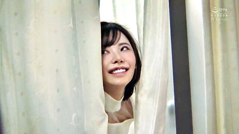 Smiling Japanese brunette teen peeking seductively through white sheer curtains