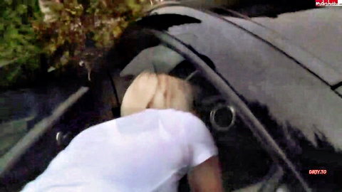 Blonde woman bends over black car window sucking two big cocks through glory holes