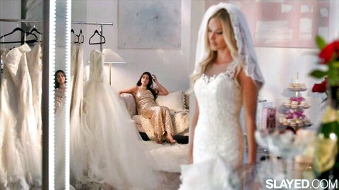 Emma Hix in white wedding dress with brunette Emma in gold gown lounging elegantly