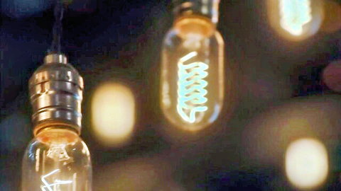 Jennifer White and Seth Gamble in dimly lit bar with glowing bulbs, Lucid Flix scene