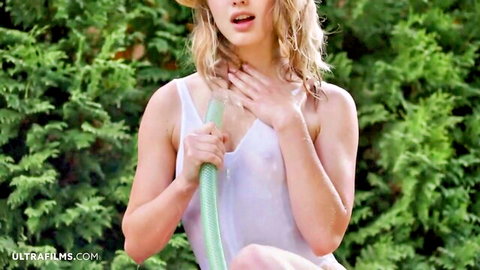 Blonde shaved babe in wet see-through tank top posing with hose outdoors