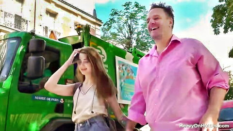 Smiling young woman holds hands with older man on sunny Paris street