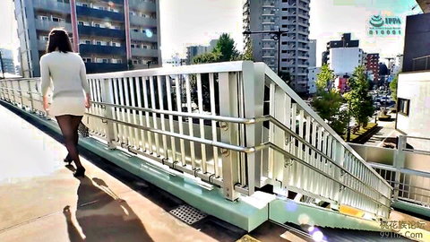 Japanese woman in miniskirt and stockings walking on urban footbridge