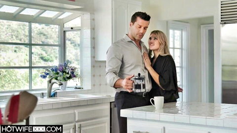 Hot blonde MILF in black robe embraces handsome stud holding coffee press in kitchen