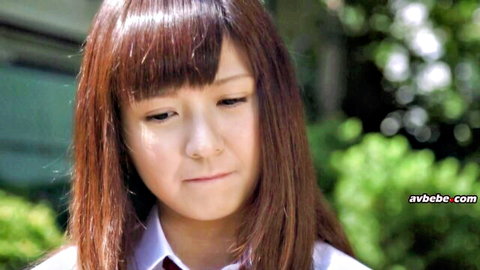 Pouty Japanese schoolgirl in uniform with bangs looking down innocently outdoors