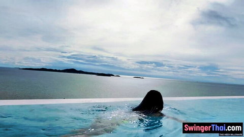 Thai amateur woman swimming nude in infinity pool with ocean view