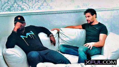 Interracial gay duo in casual conversation on couch, teasing fantasy buildup
