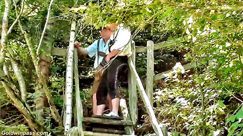 Bearded man in traditional suspenders on forest bridge, outdoor hike