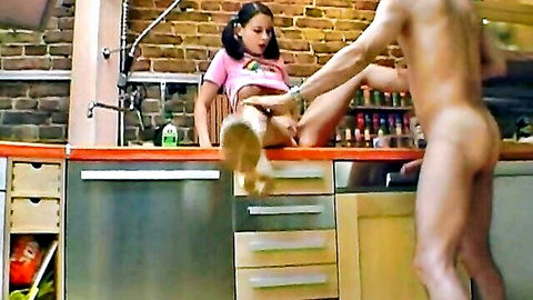 Teenage girl in pink top spreads legs for naked man's touch in kitchen