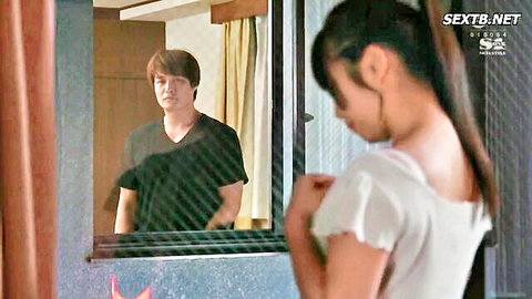 Asian brunette in off-shoulder top teases handsome guy through glass window with intense stare
