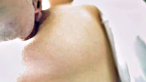 Bearded man passionately kissing woman's pale soft breast skin closeup