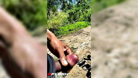 Dark-skinned man masturbating erect penis in public outdoors