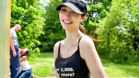 Brunette in tank top smiles teasingly outdoors with kneeling woman and man behind