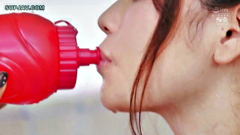 Asian redhead woman teasingly sucking on red water bottle spout