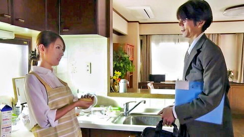 Japanese housewife in apron talks with suited man in kitchen