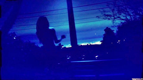 Nude woman silhouette on balcony at night with city lights
