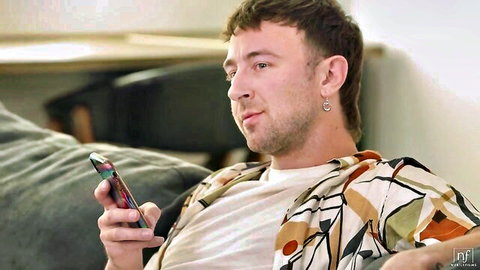 Young man lounging with phone in Nubile Films' Fucking My Brothers Friend
