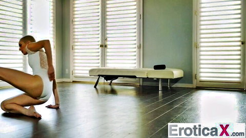 Slim ballerina in white bodysuit poses seductively, legs spread
