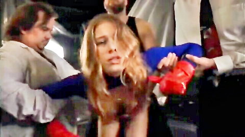 Blonde superheroine in blue costume grabbed by men in peril scene