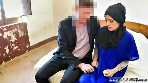Intimate moment between suited man and hijab-wearing woman on bed