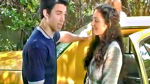 Flirty brunette in blazer chats with handsome guy by yellow taxi